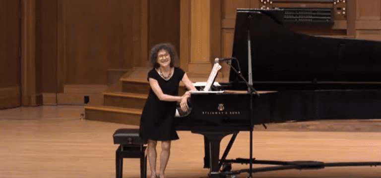 Catherine Kautsky stands on stage in front of a grand piano