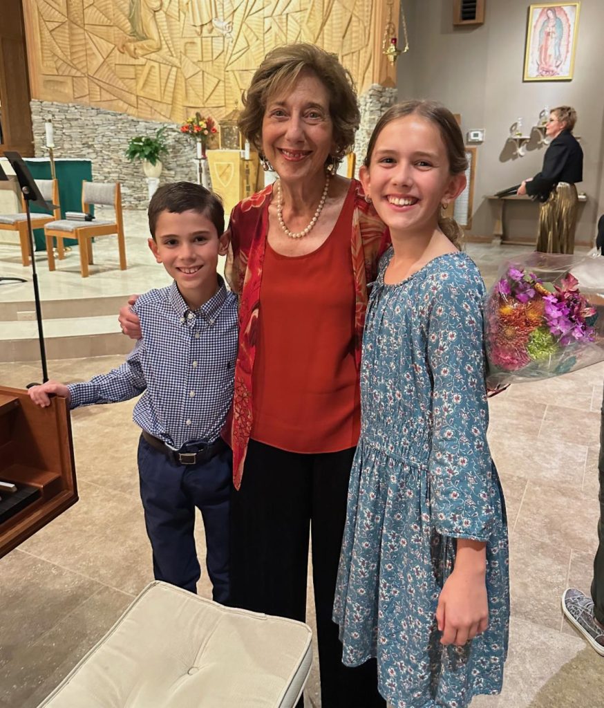 Students of Phyllis Lehrer posing for a picture with her in a church sanctuary.