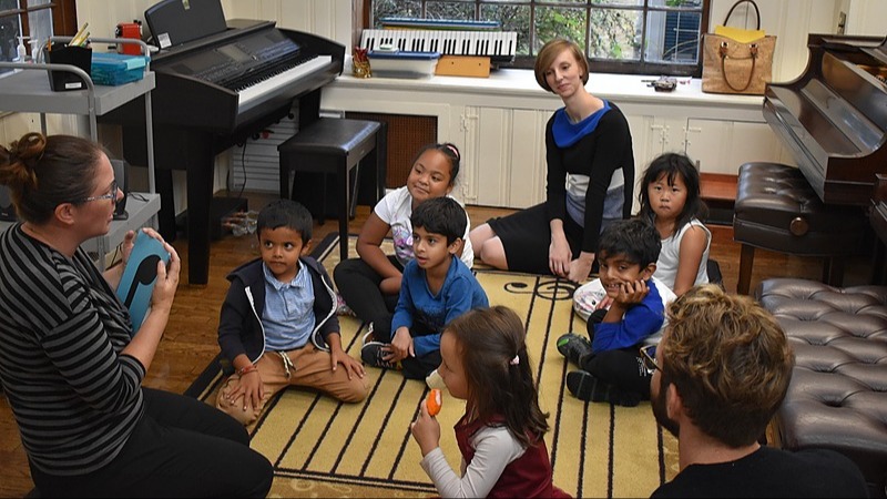 An image showing two instructors working with children on reading and rhythm skills.