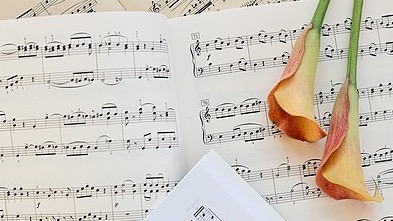 Sheet music photographed with flowers on top.