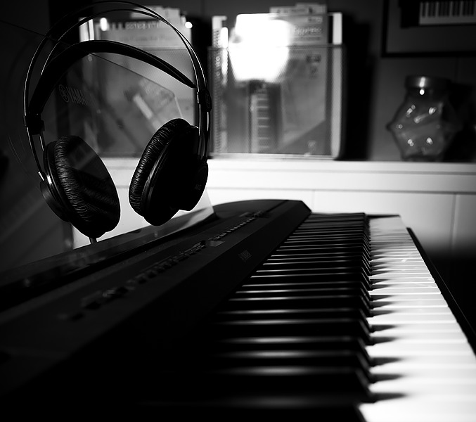 A black-and-white photograph featuring a keyboard and headphones.
