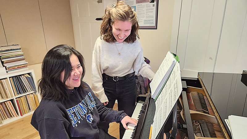 Alexa Stier photographed with an adult piano student at the instrument.